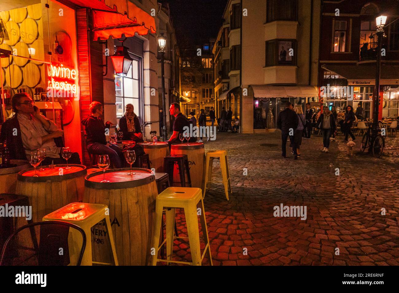 Hocker, ein Tisch und ein Neonschild auf Kopfsteinpflaster vor einer Weinbar in Plovdiv, Bulgarien Stockfoto