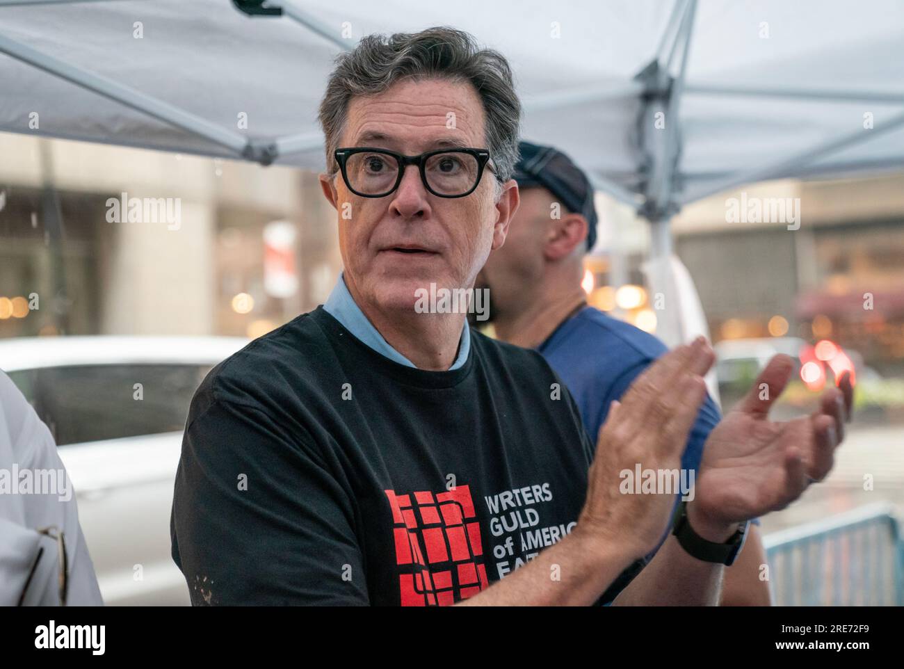 Stephen Colbert serviert Eiscreme an markante Mitglieder der Writers Guild of America, die am 25. Juli 2023 trotz starken Regens vor dem Büro von Warner Brothers Discovery in New York pokitieren. Stockfoto