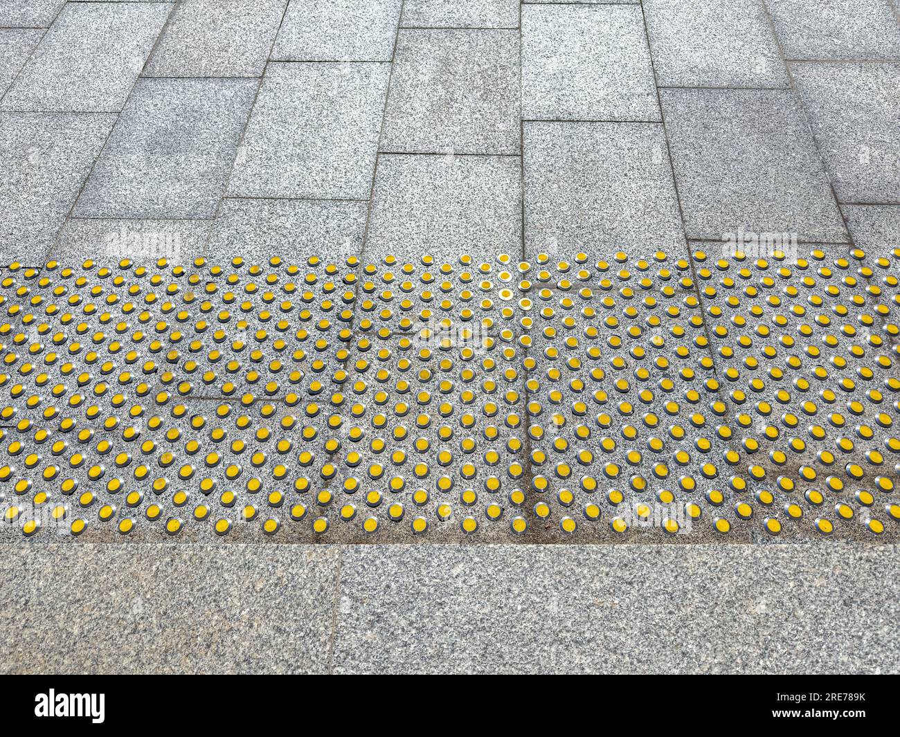 Taktile Fußbodenmarkierungen auf dem Gehweg als Orientierungshilfe für sehbehinderte Personen. Oberfläche für Sehbehinderte. Stockfoto