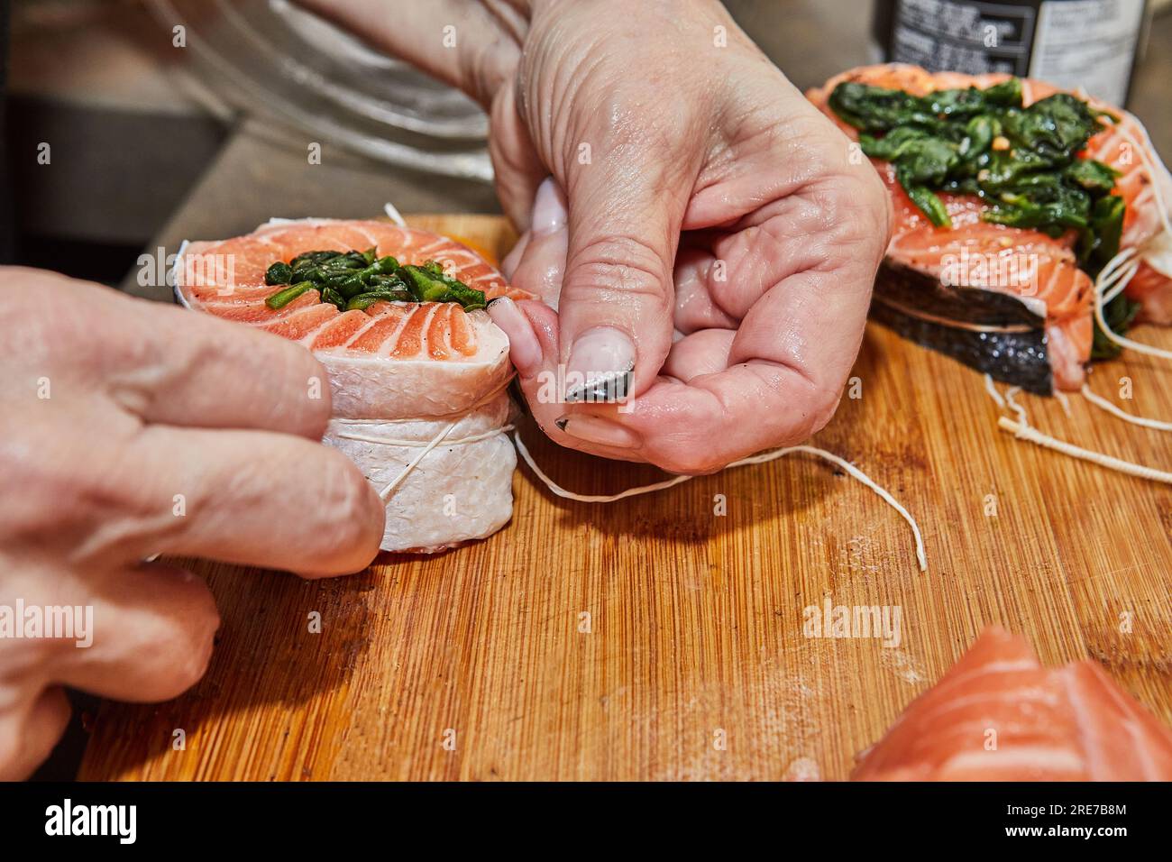 Der Küchenchef bereitet Lachs mit Spinat und gebackener Zitrone und Sauce zu. Französische Gourmetküche. Stockfoto