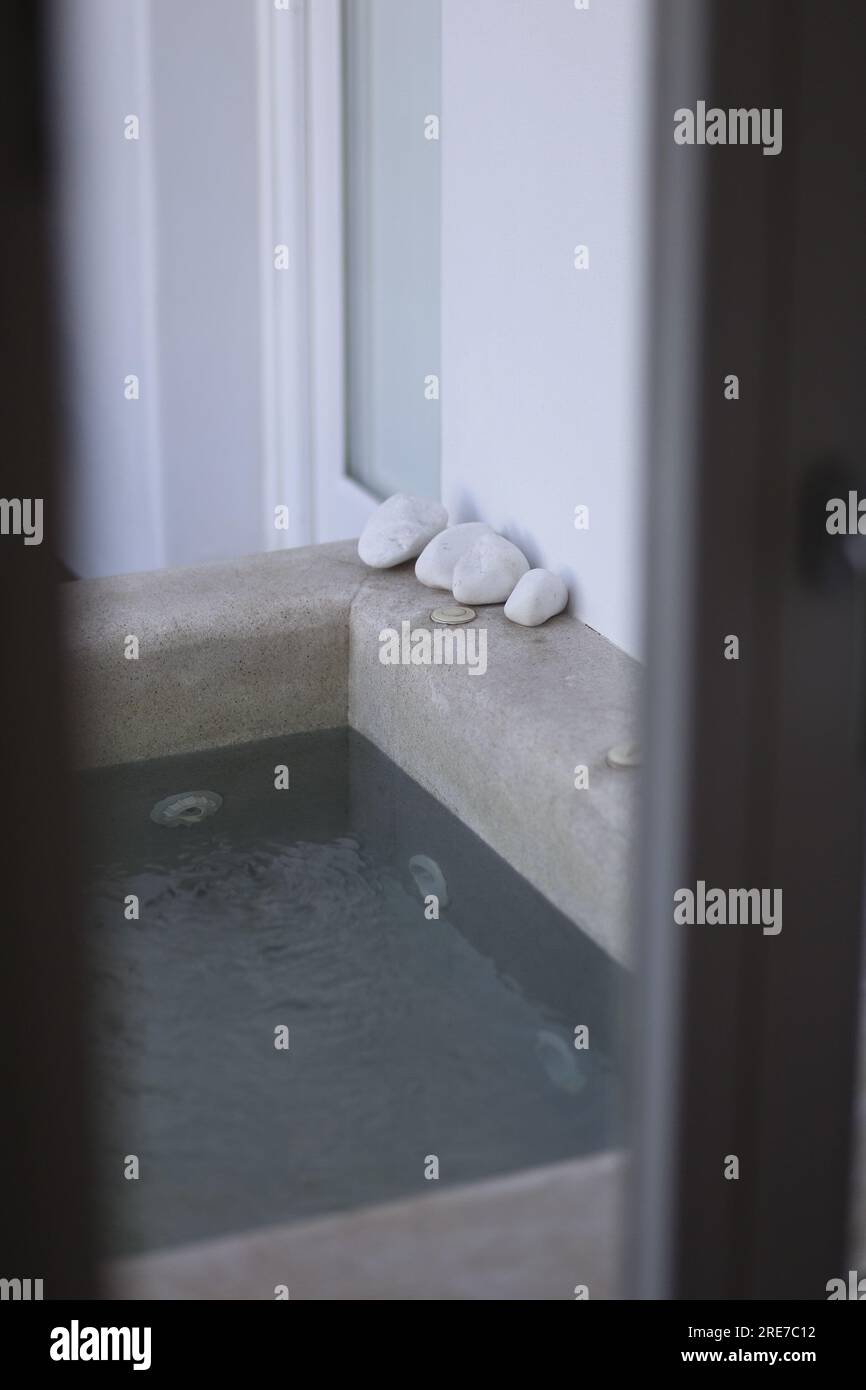 Dekoration entspannende weiße Kopfsteinpflastersteine an der Ecke eines winzigen einheimischen Swimmingpools Stockfoto