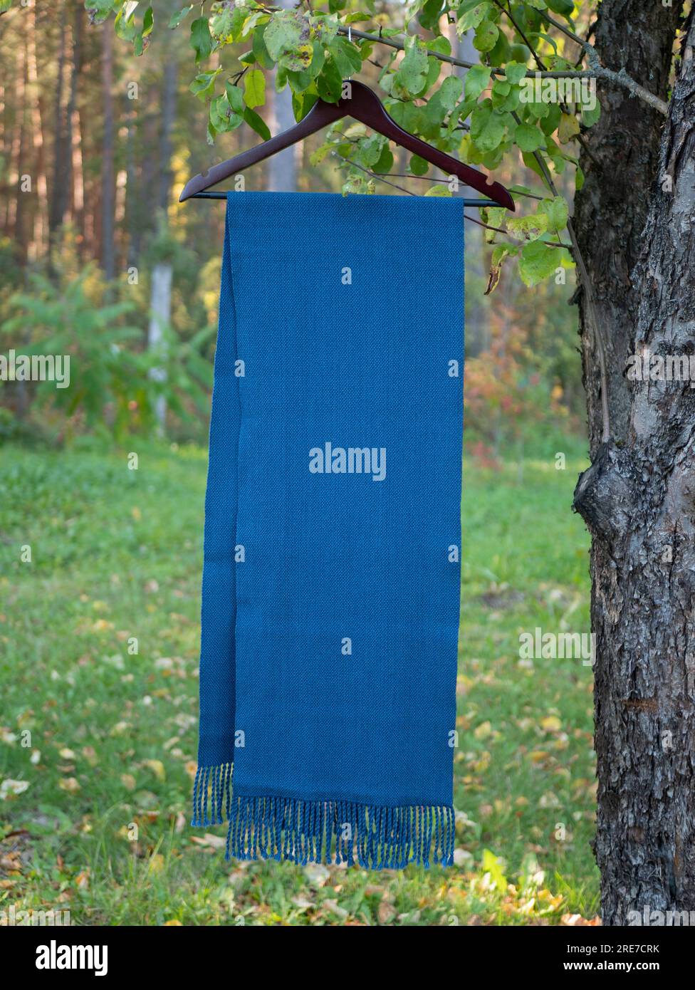 Leuchtend blauer Schal oder Schal mit Fransen an einem Hänger im Freien, vertikales Format und selektiver Fokus Stockfoto