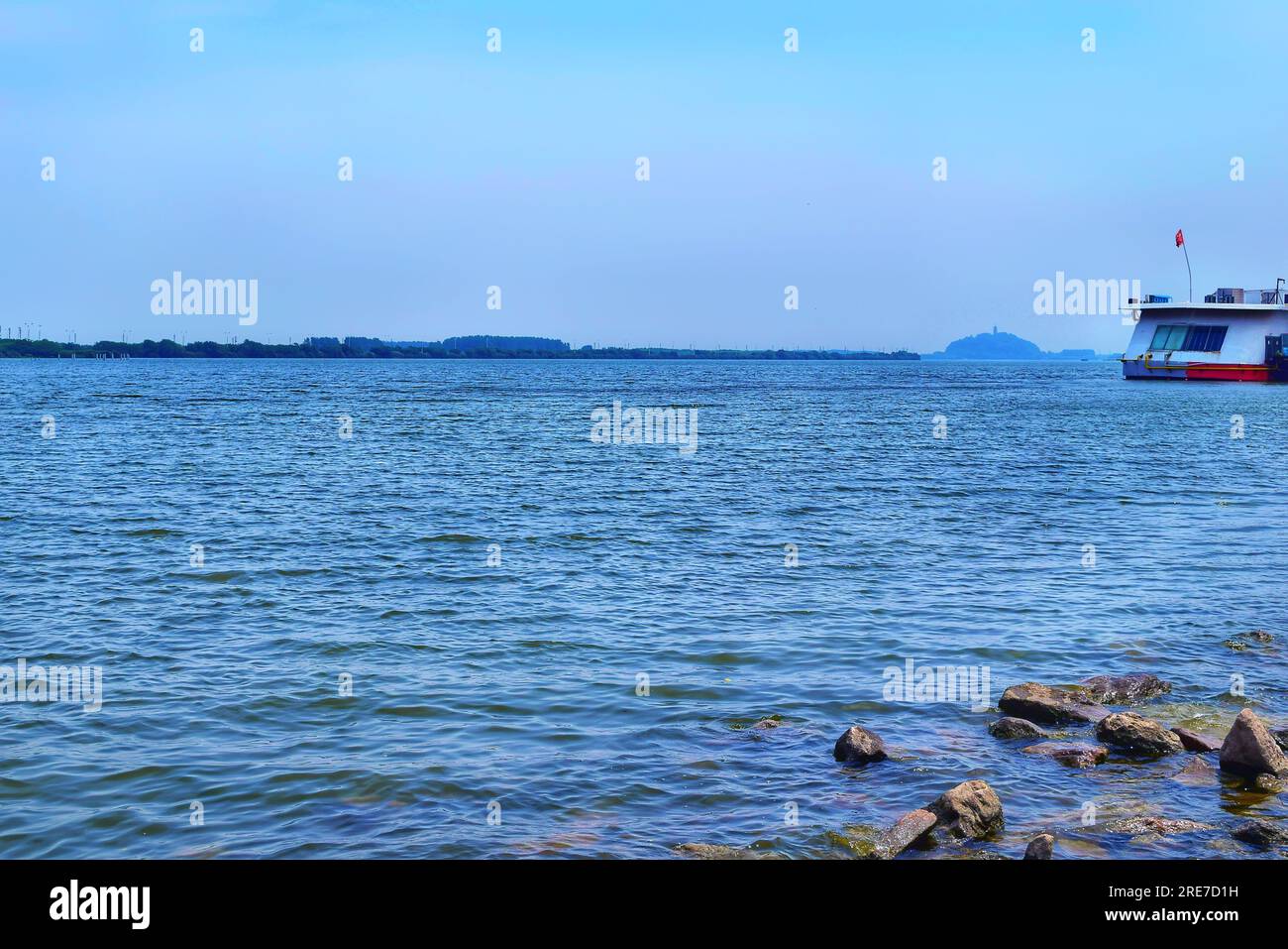 Tauchen Sie ein in den ruhigen Reiz eines malerischen Flusses in China, dessen kristallklares blaues Wasser den weiten blauen Himmel unter dem warmen emb reflektiert Stockfoto