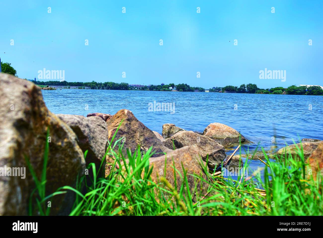 Tauchen Sie ein in den ruhigen Reiz eines malerischen Flusses in China, dessen kristallklares blaues Wasser den weiten blauen Himmel unter dem warmen emb reflektiert Stockfoto