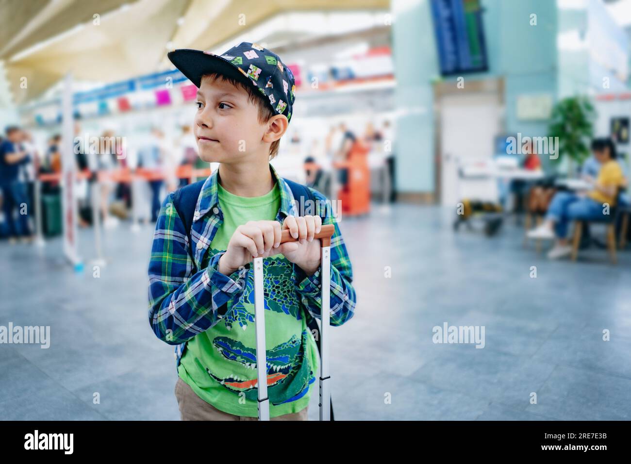 Süßer weißer Junge am Flughafen mit Rucksack und Koffer. Reisekonzept. Hochwertiges Foto Stockfoto