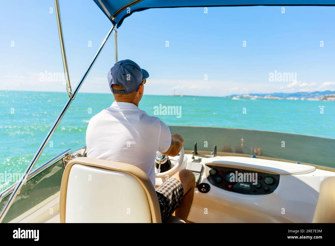 Bach-Blick auf einen Mann mittleren Alters, der eine Luxusmotoryacht fährt. Kapitän am Steuer des Motorboots. Bild mit selektivem Fokus Stockfoto