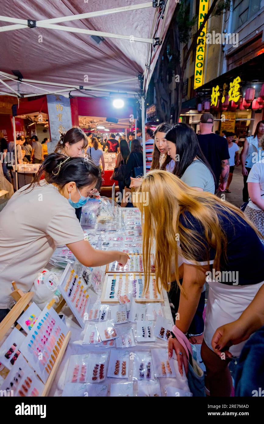 Frauen, die während des (chinesischen) Mondneujahrs in der Dixon Street (China Town) in Sydney in Australien auf einen Verkaufsstand schauen, an dem künstliche oder gefälschte Nägel verkauft werden Stockfoto