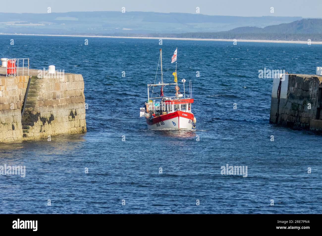 Rot-weißes Fischerboot, das nach einem Tag auf dem Meer zurück in den Hafen fährt Stockfoto