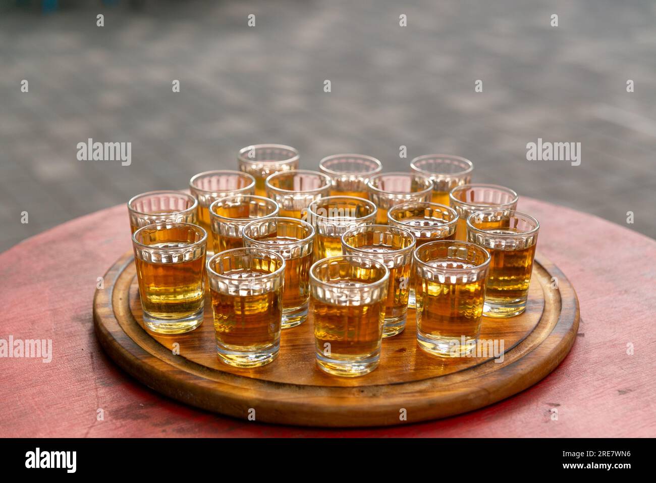 Kleine Gläser gefüllt mit Brandy auf einem Holztablett. Alkoholisches Buffet im Straßencafé. Schnaps mit alkoholischem Getränk für den Geschmack. Stockfoto