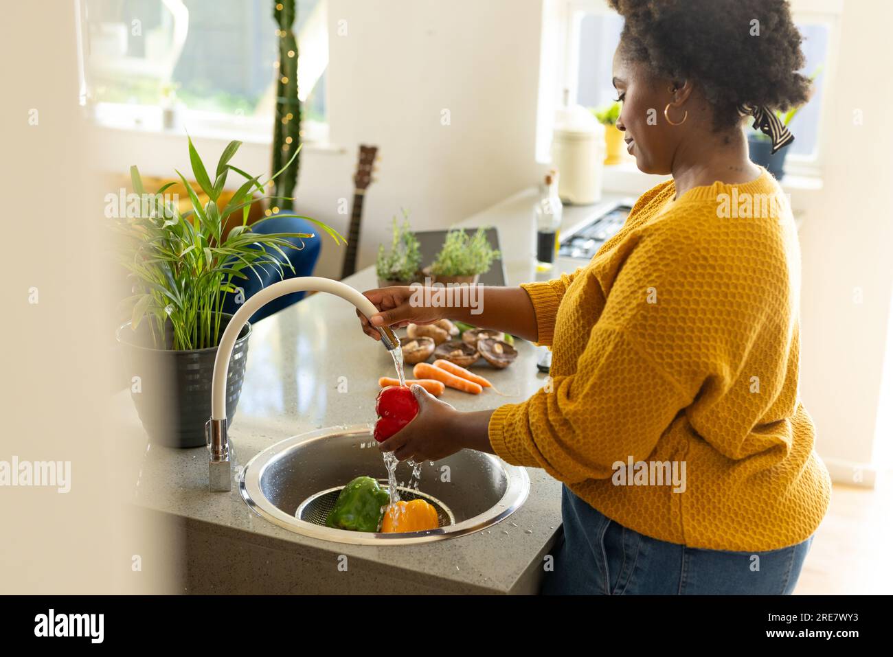 Eine große afroamerikanische Frau spült Gemüse in der Küche Stockfoto