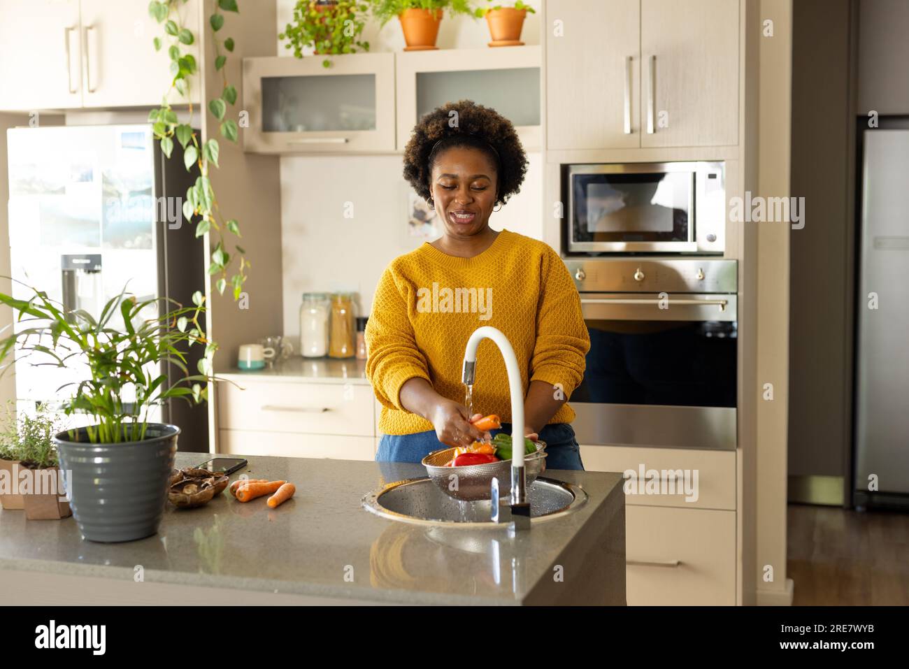 Eine glückliche afroamerikanerin, die Gemüse in der Küche spült Stockfoto