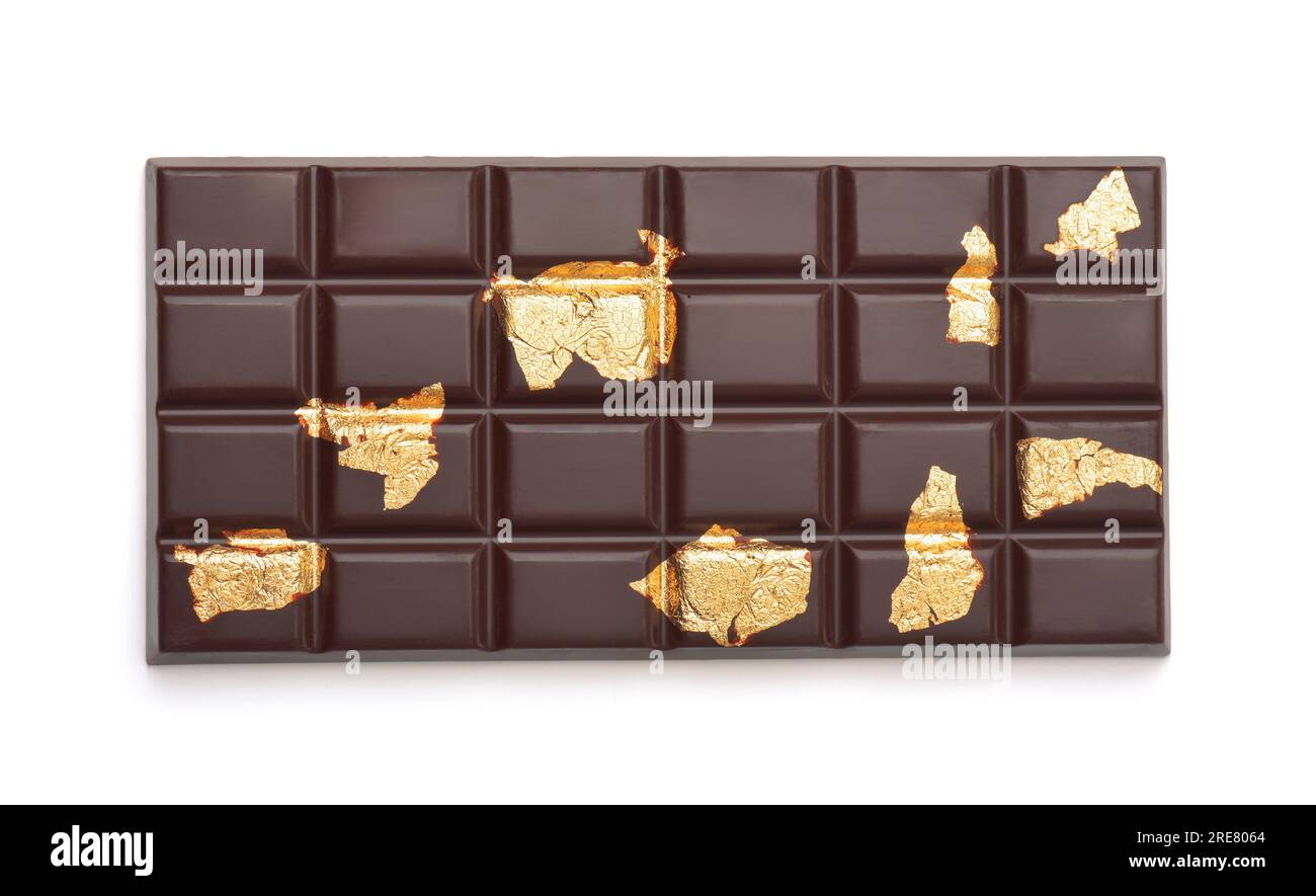 Blick von oben auf eine dunkle Schokoladenbar mit Stücken essbarer Goldblätter isoliert auf Weiß Stockfoto