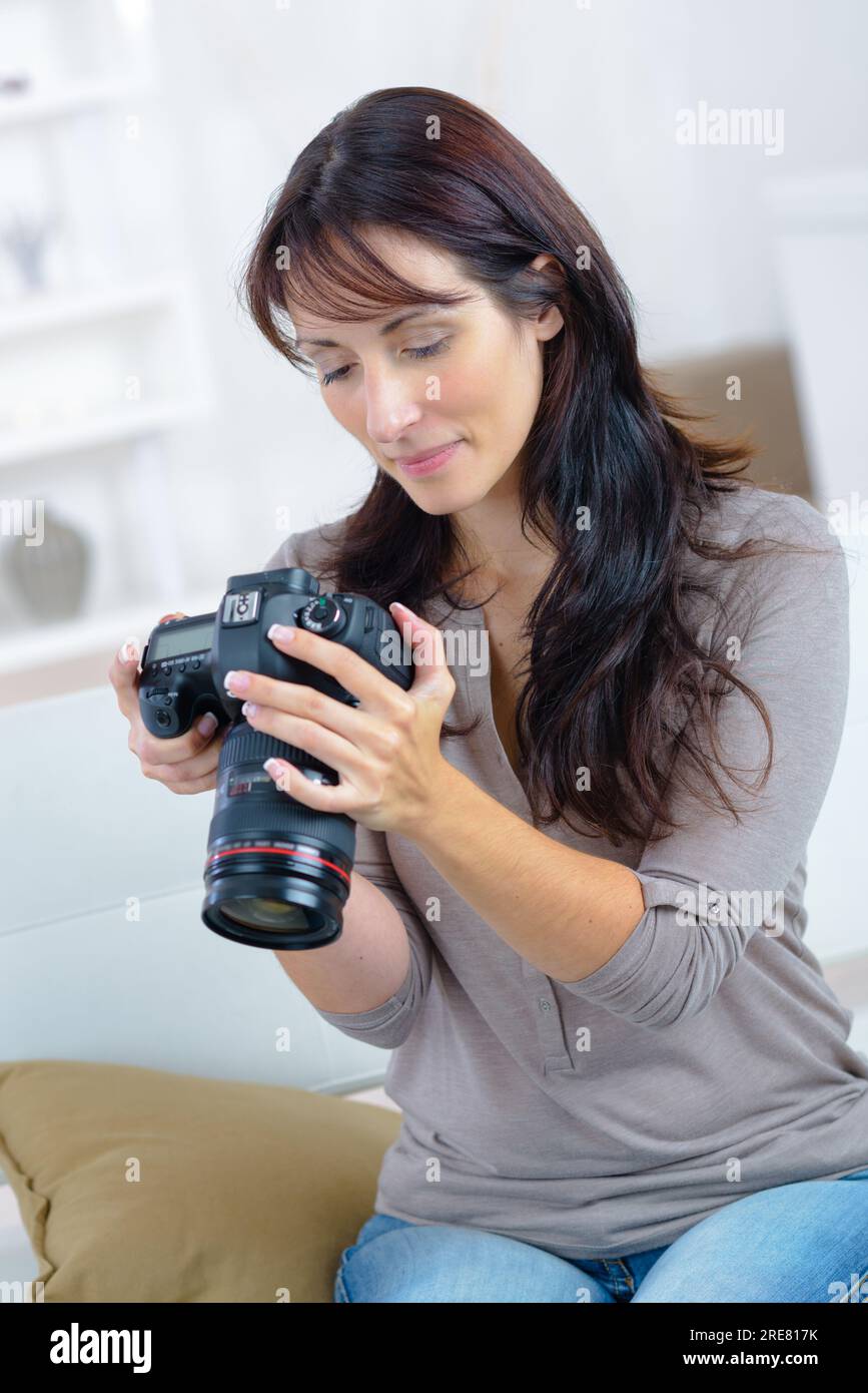 glückliche Frau Scheck Fotos vor der Kamera beim Sitzen auf dem sofa Stockfoto