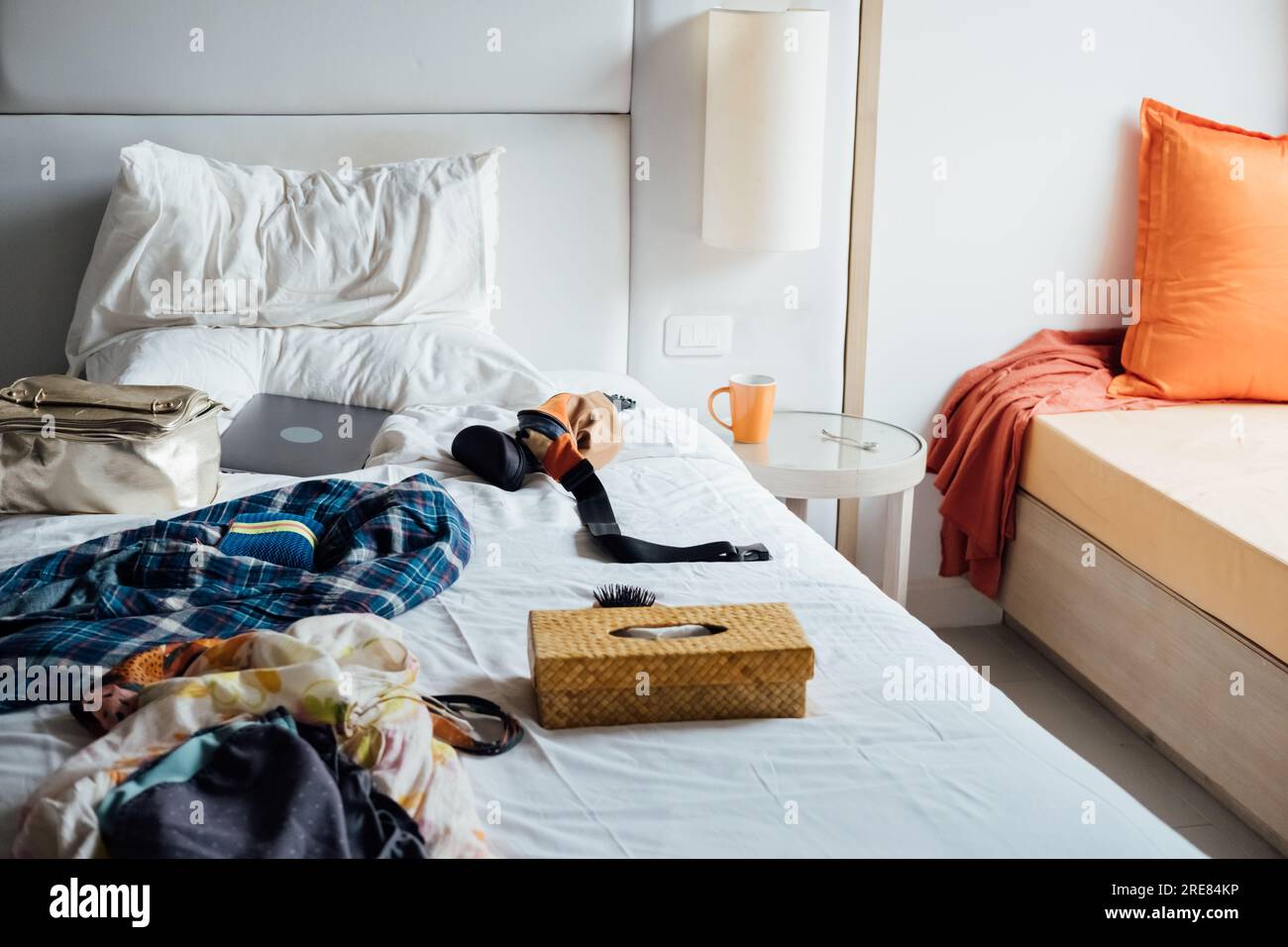 Chaos im Zimmer. Frauenkleidung, Computer auf dem Bett Stockfoto