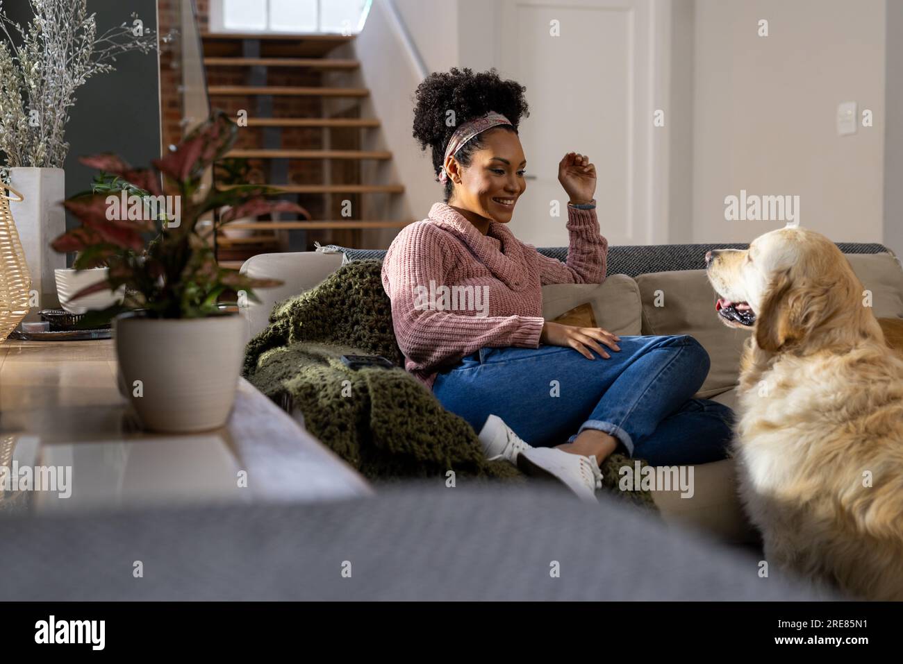 Glückliche, birassische Frau, die zu Hause Hund streichelt Stockfoto