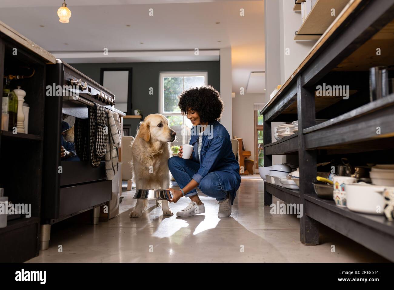 Glückliche, birassische Frau, die Hundefutter in der Küche serviert Stockfoto