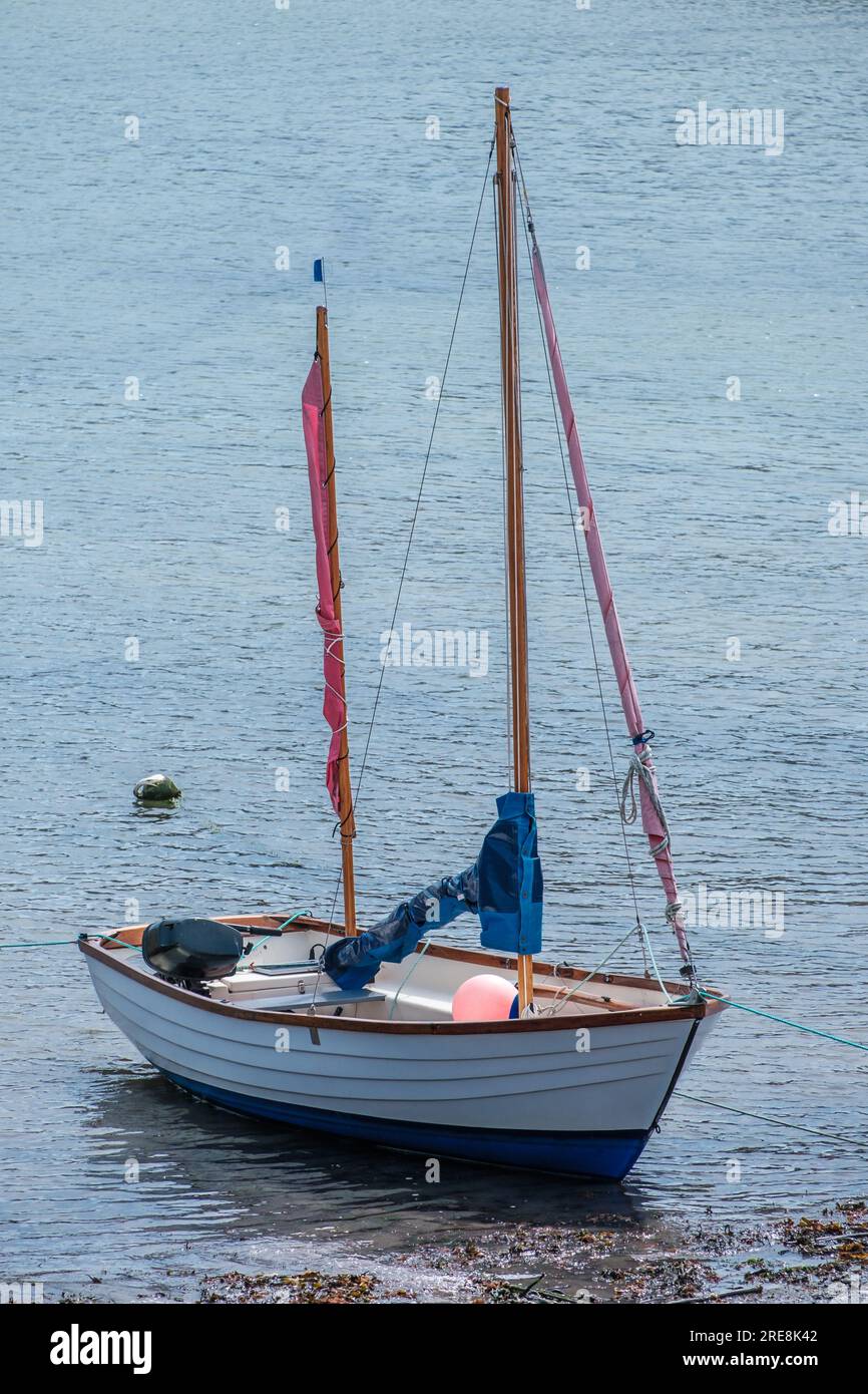 Kleines Segelboot mit seinen Segeln, die in flachem Wasser liegen. Stockfoto