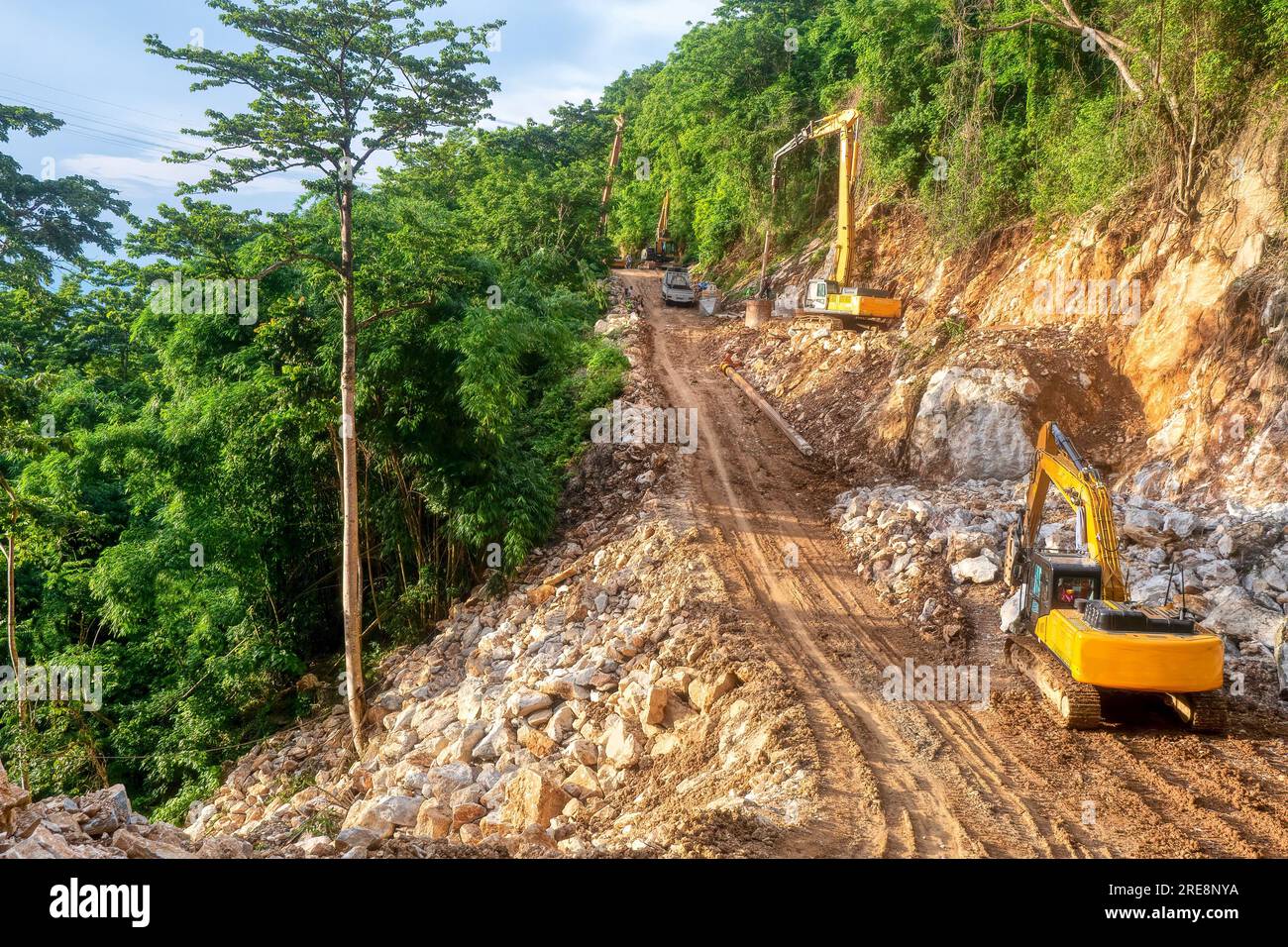 Schwere Baumaschinen im Einsatz als Fundament für eine neue Straße durch ein steiles, bewaldetes Gebiet auf Mindoro Island, Philippinen. Stockfoto