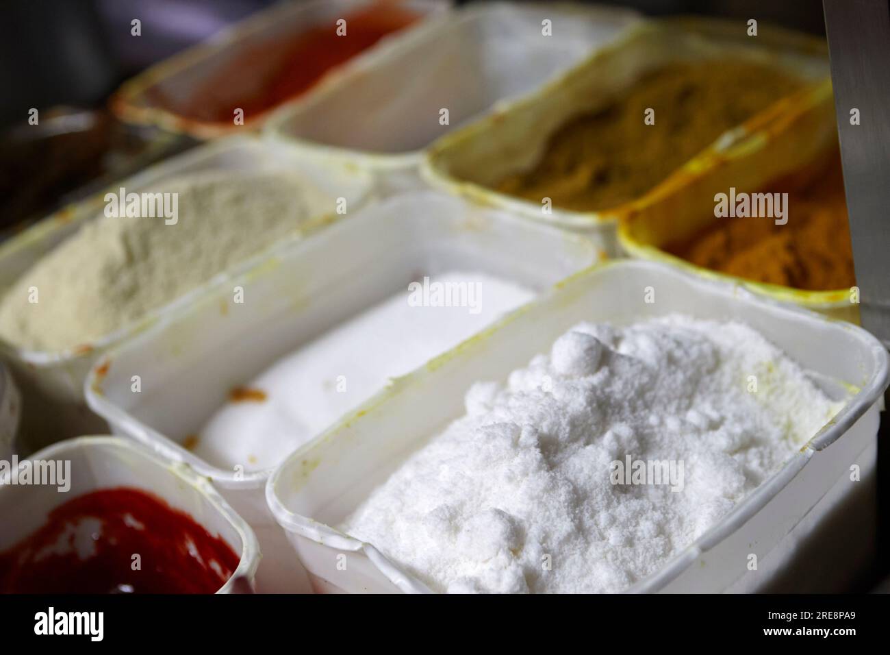 Behälter mit Gewürzen und Saucen, fertig zum Kochen in einem indischen Restaurant Stockfoto
