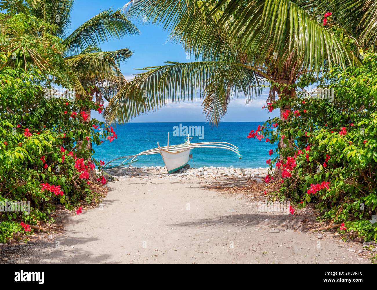Eine farbenfrohe tropische Inselszene auf den Philippinen, mit einem traditionellen hölzernen Auslegerboot banca an einem weißen Strand in der Occidental Mindoro Provinz. Stockfoto