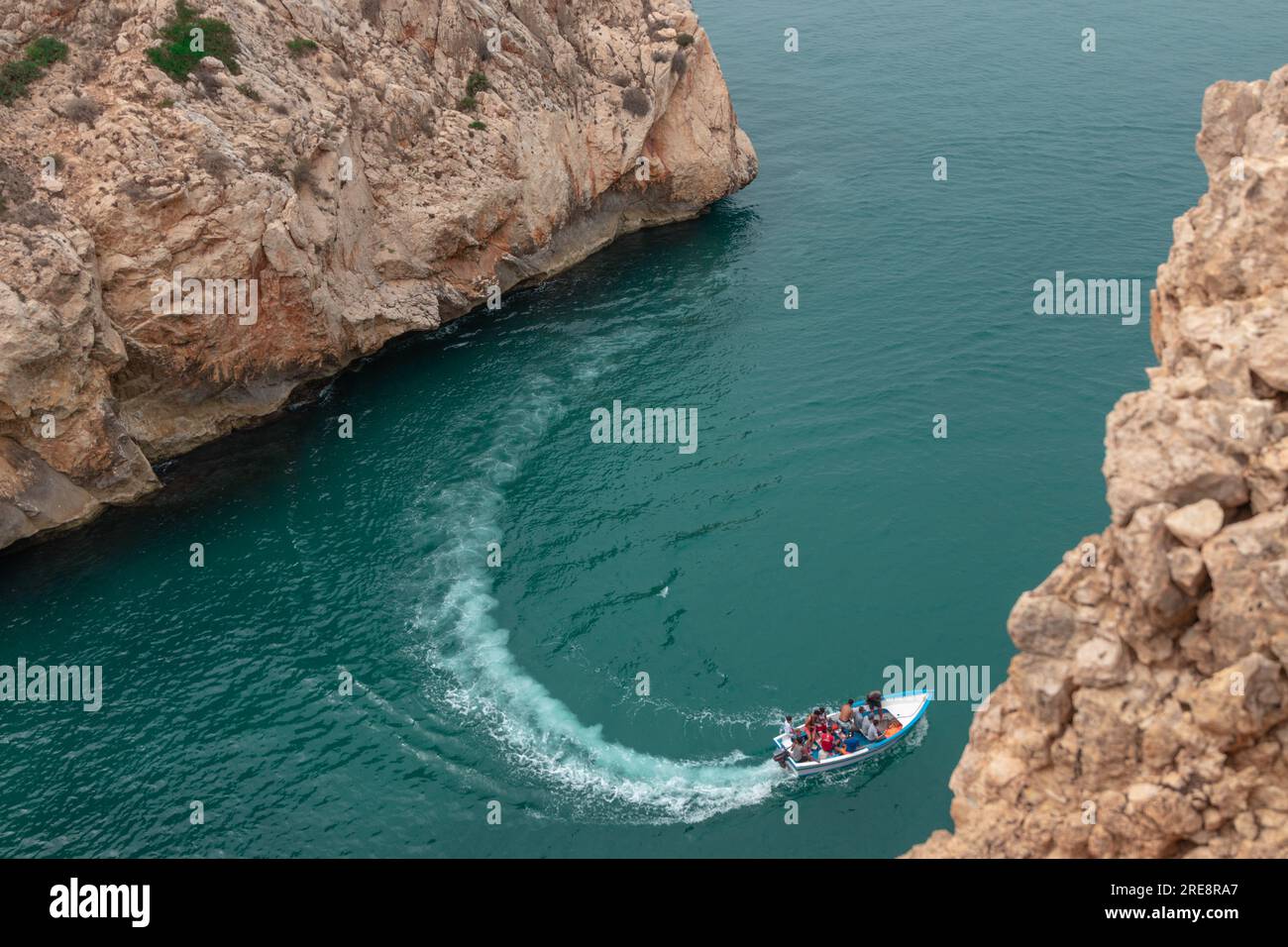 Ein Blick von oben auf ein Boot, das zwischen zwei großen felsigen Bergen an einem der Strände der Stadt El Jebha, Marokko, fährt Stockfoto