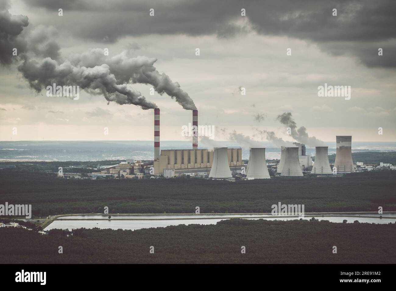 Aus der Vogelperspektive: Kraftwerk, Rauch aus Schornsteinen und Kohlebergwerk in Belchatow unter launischem, wolkigen Himmel, Polen Stockfoto