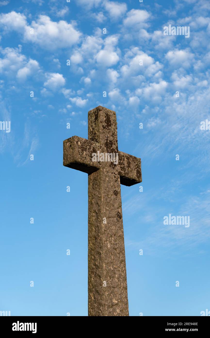 Blick aus dem niedrigen Winkel auf ein uraltes Steinkreuz unter einem hellblauen Himmel in Erinnerung an die Toten und repräsentiert Hoffnung, Tod und Trauer Stockfoto