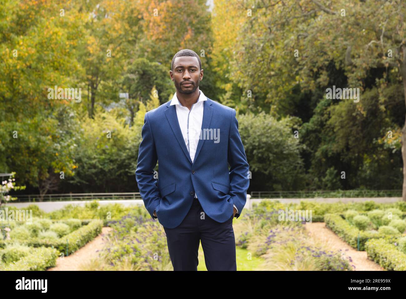 Ein aufmerksamer afroamerikanischer Bräutigam stand am Hochzeitstag im sonnigen Garten Stockfoto