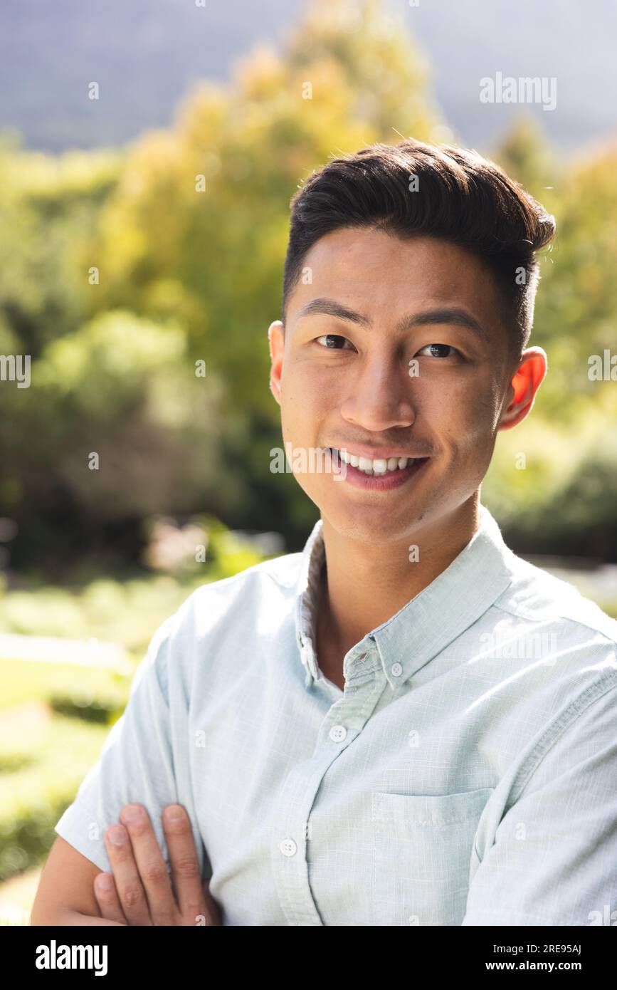 Porträt eines glücklichen Asiaten, der im sonnigen Garten lächelt Stockfoto