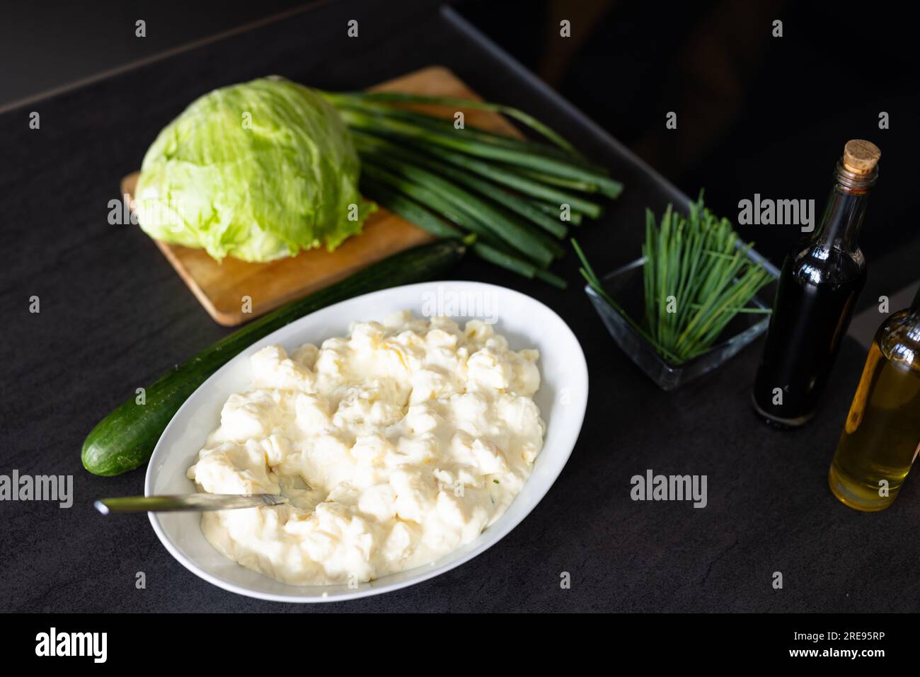 Nahaufnahme von Frischkäse in der Schüssel und Gemüse auf der Arbeitsfläche in der Küche Stockfoto