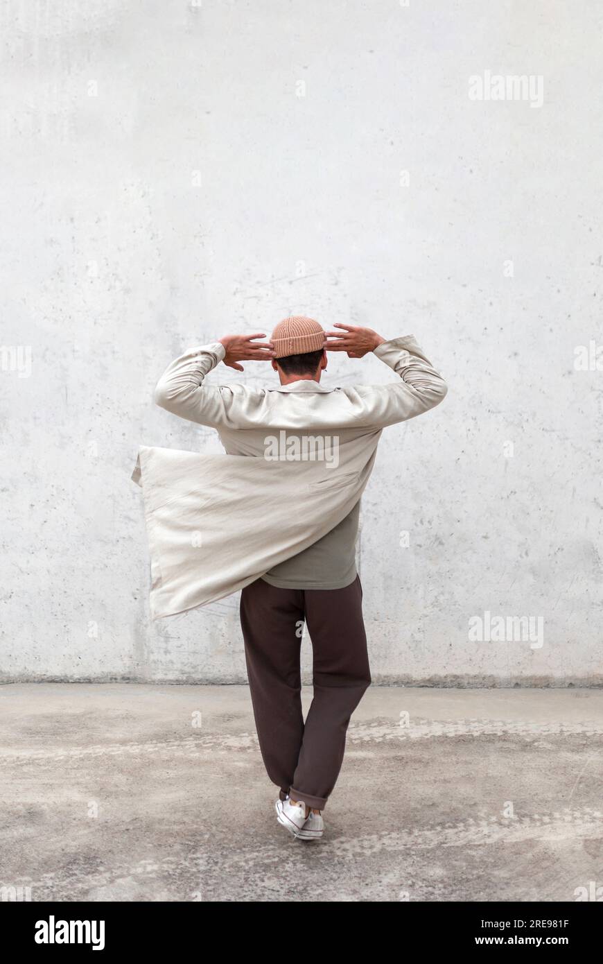 Rückansicht eines anonymen männlichen Breakdancers, der in der Stadt auftrat Bereich in der Nähe der grauen Gebäudewand Stockfoto