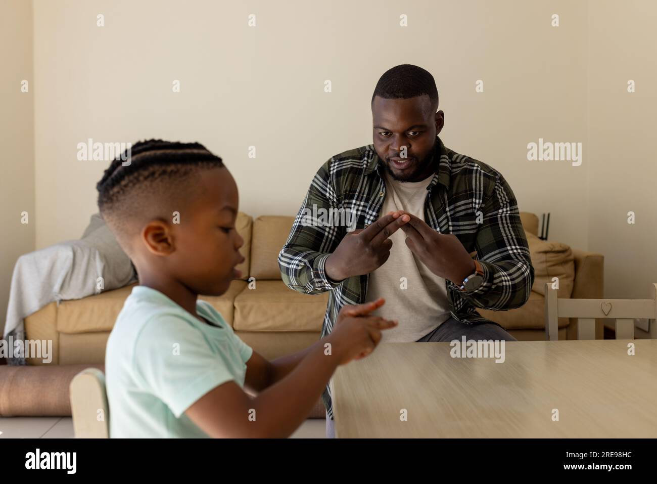 Glücklicher afroamerikanischer Vater und Sohn, die zu Hause Gebärdensprache praktizieren Stockfoto