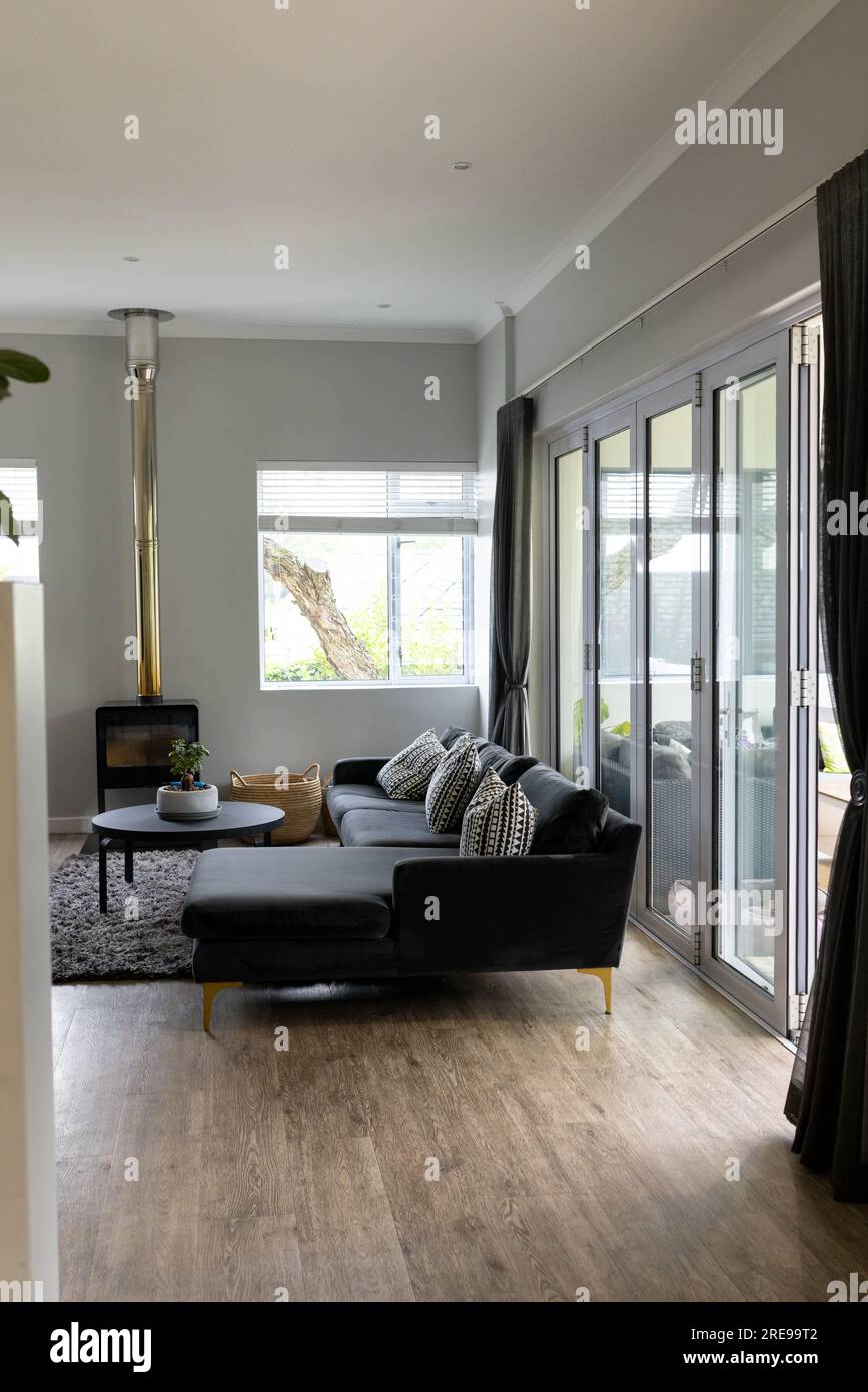 Allgemeiner Blick auf das Wohnzimmer mit Sofa, Kamin und Fenstern Stockfoto