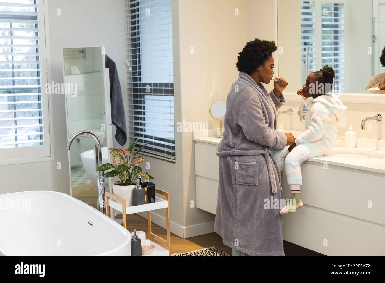 afroamerikanische Mutter und Tochter waschen zu Hause im Badezimmer Zähne, Kopierraum Stockfoto