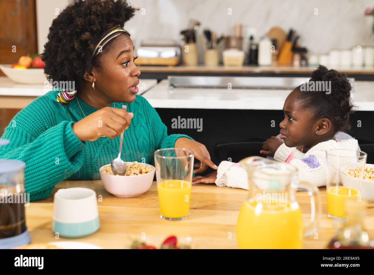 afroamerikanische Mutter und Tochter sitzen am Tisch und frühstücken zu Hause Stockfoto