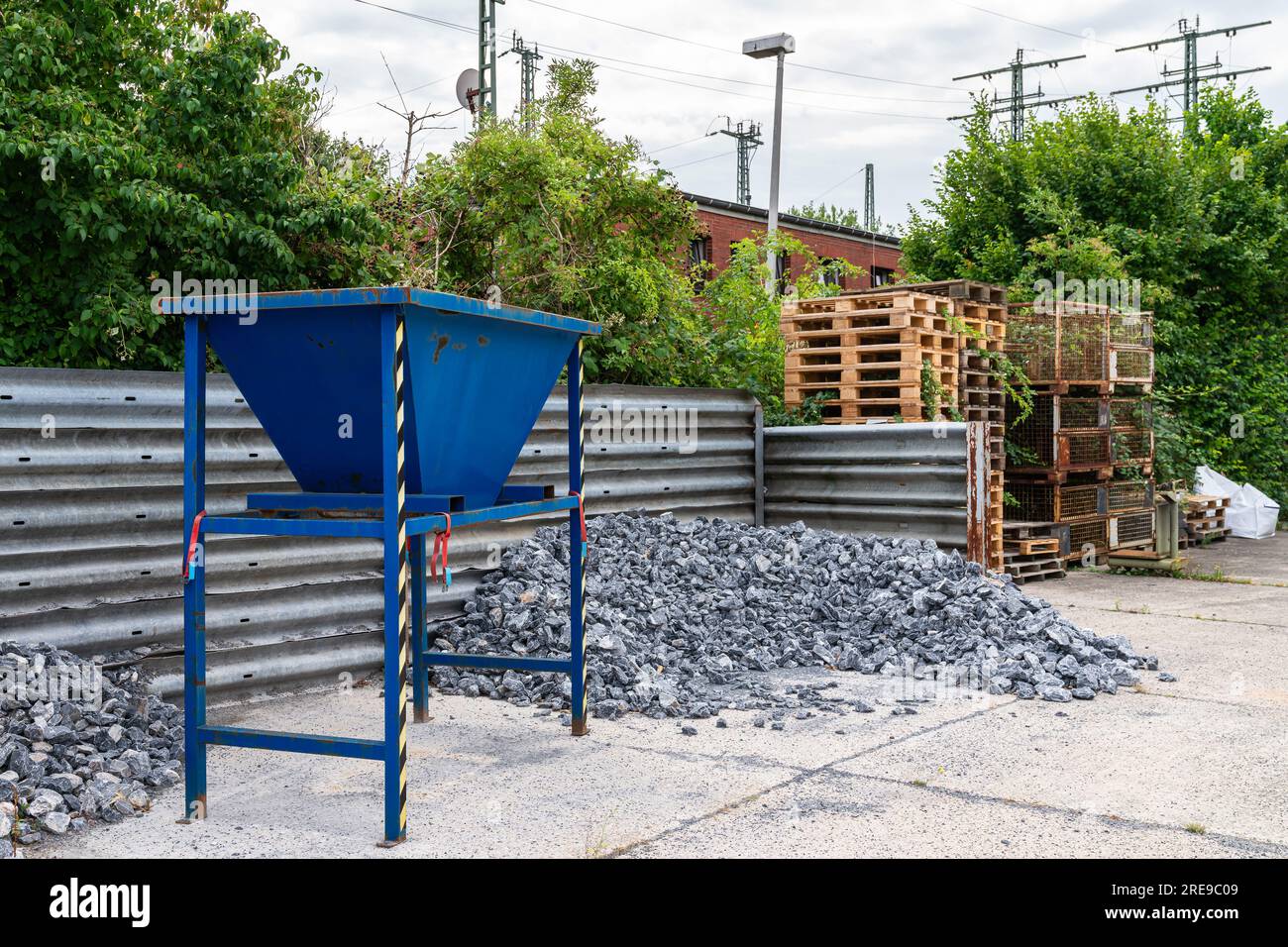 Kiesellager mit Steinbrecher und Haufen von Graustein- und Holzpaletten. Stockfoto