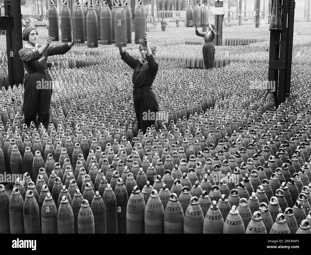 Horace Nicholls - weibliche Munitionsarbeiter führen 6-Zoll-Howitzer-Patronen, die in der National Shell Filling Factory in Chilwell auf den Boden abgesenkt werden. Stockfoto