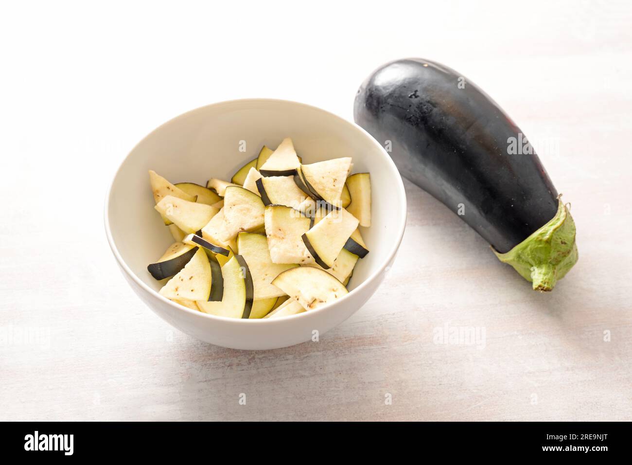 Aubergine, ganz und gehackt in einer Schüssel, Zutat für verschiedene Gemüsespezialitäten, gesundes vegetarisches Kochkonzept, Kopierraum, ausgewählter Fokus, eng Stockfoto