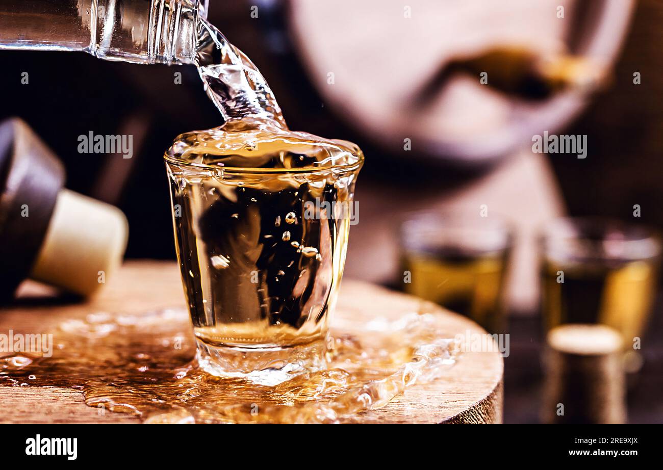 Ein Glas goldenen Rum mit Flasche. Flasche, die Alkohol in ein kleines Glas gießt. Brasilianisches Exportsgetränk. Brasilianisches Erzeugnis für die Ausfuhr, destilliertes drin Stockfoto