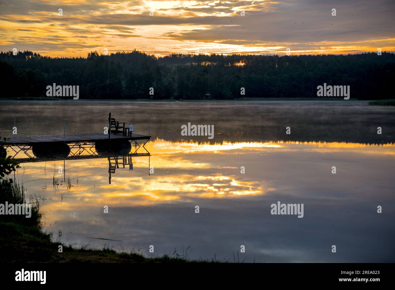 Bank am Pier, mit See und Wald, Himmel reflektiert im Wasser, Sonnenaufgang Stockfoto