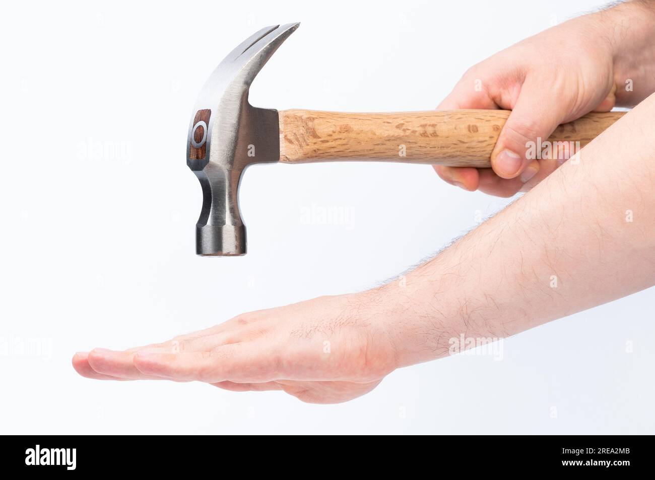 Schlagen Sie die Hand mit einem isolierten Hammer auf weißem Studiohintergrund Stockfoto