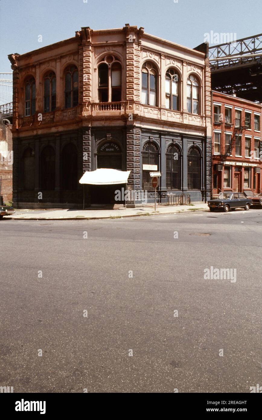 AJAXNETPHOTO. JULI 1975. BROOKLYN, NEW YORK, USA. - OLD BANK - BROOKLYN BRIDGE TOWER, DER SICH HINTER GESCHÄFTSGEBÄUDEN AUS DEM 19. JAHRHUNDERT AN DER ECKE DER FRONT STREET UND DER CADMAN PLAZA WEST ERHEBT; DIE ALTE FULTON FERRY BANK UND AUF DER LINKEN SEITE DAS ÄLTESTE VERBLEIBENDE KOMMERZIELLE GEBÄUDE AUS DEM 19TH. JAHRHUNDERT UNTER DEM DECK DER BROOKLYN BRIDGE, DIE DEN EAST RIVER ZWISCHEN PARK ROW MANHATTAN UND SANDS STREET, BROOKLYN, NEW YORK CITY, ÜBERSPANNT. FOTO: JONATHAN EASTLAND/AJAXREF:601874 137 2 Stockfoto