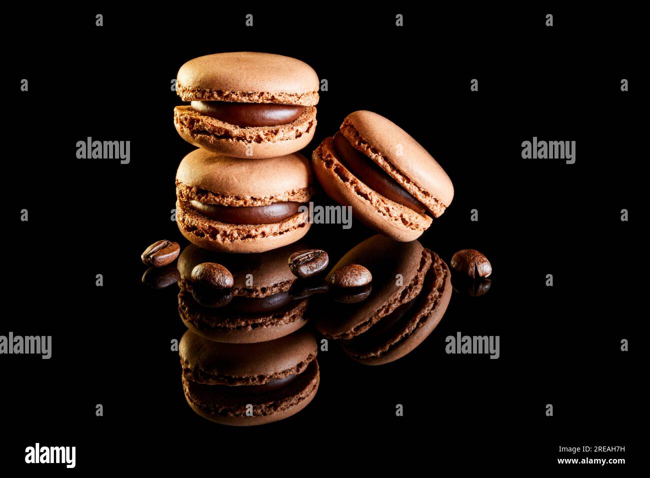 Aromatisierte farbige Makronen auf reflektierender Oberfläche mit Kaffeebohnen Stockfoto