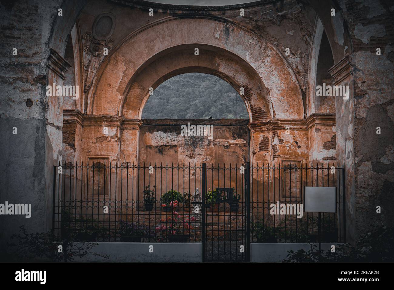 Ruinen eines alten religiösen Gebäudes mit Säulen und Bögen, die durch ein Metalltor eingezäunt sind, in Antigua, Guatemala Stockfoto