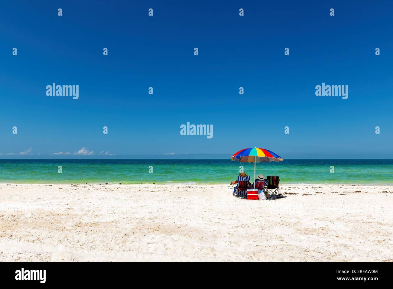 Sonniger Strand und tropisches Meer mit farbenfrohem Sonnenschirm Stockfoto Sonniger Strand und tropisches Meer mit farbenfrohem Sonnenschirm Stockfoto