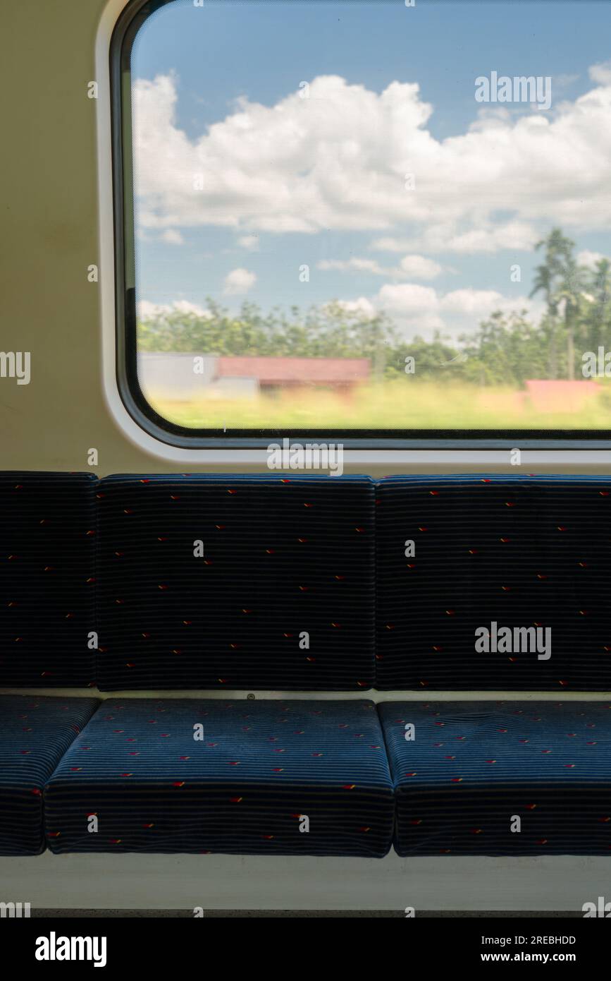 Blick auf die Landschaft vom Zugfenster mit leerem Sitzplatz in Malaysia Stockfoto