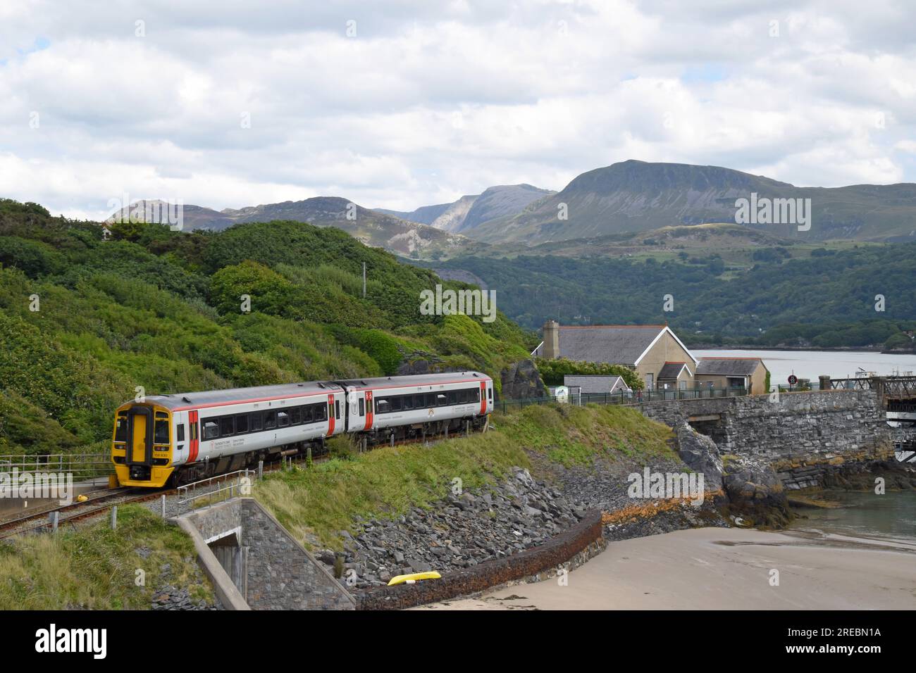 Ein Transport für Wales Klasse 158 Express DMU nähert sich Barmouth Station nach Überquerung der Barmouth Bridge, Gwynedd, Wales, Juli 2023 Stockfoto