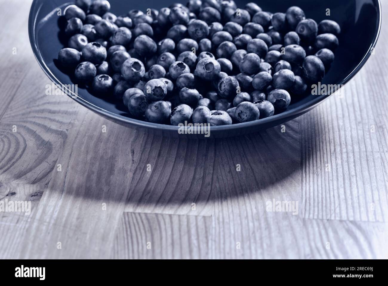 Heidelbeeren oder Heidelbeeren in Blauteller auf dem Tisch, Blaubeeren mit Rinde, monochrome Stille Leben, gesunde Ernährung Stockfoto