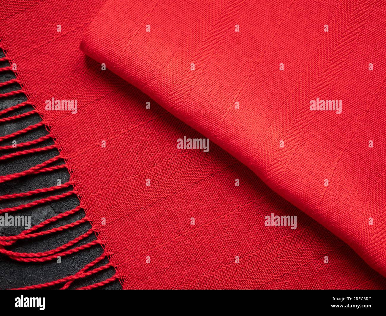 Eleganter, dünner handgewebter Schal in sattem Rot mit auffälligen strukturierten Streifen und Fransen, Nahaufnahme und selektiver Fokussierung Stockfoto