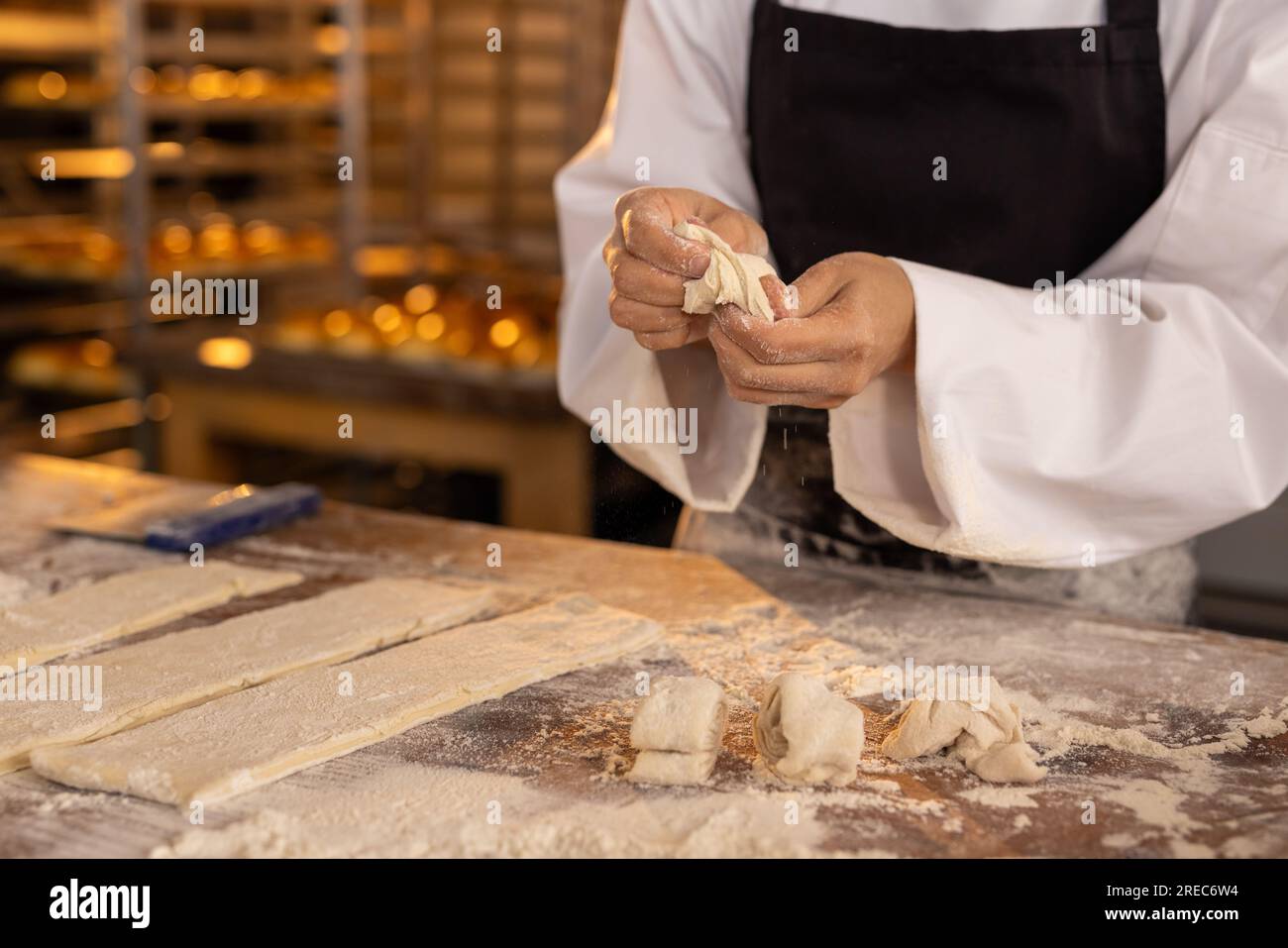 Asiatische Bäckerin in Bäckerei Küche trägt Schürze und bildet Teig, Kopierraum Stockfoto